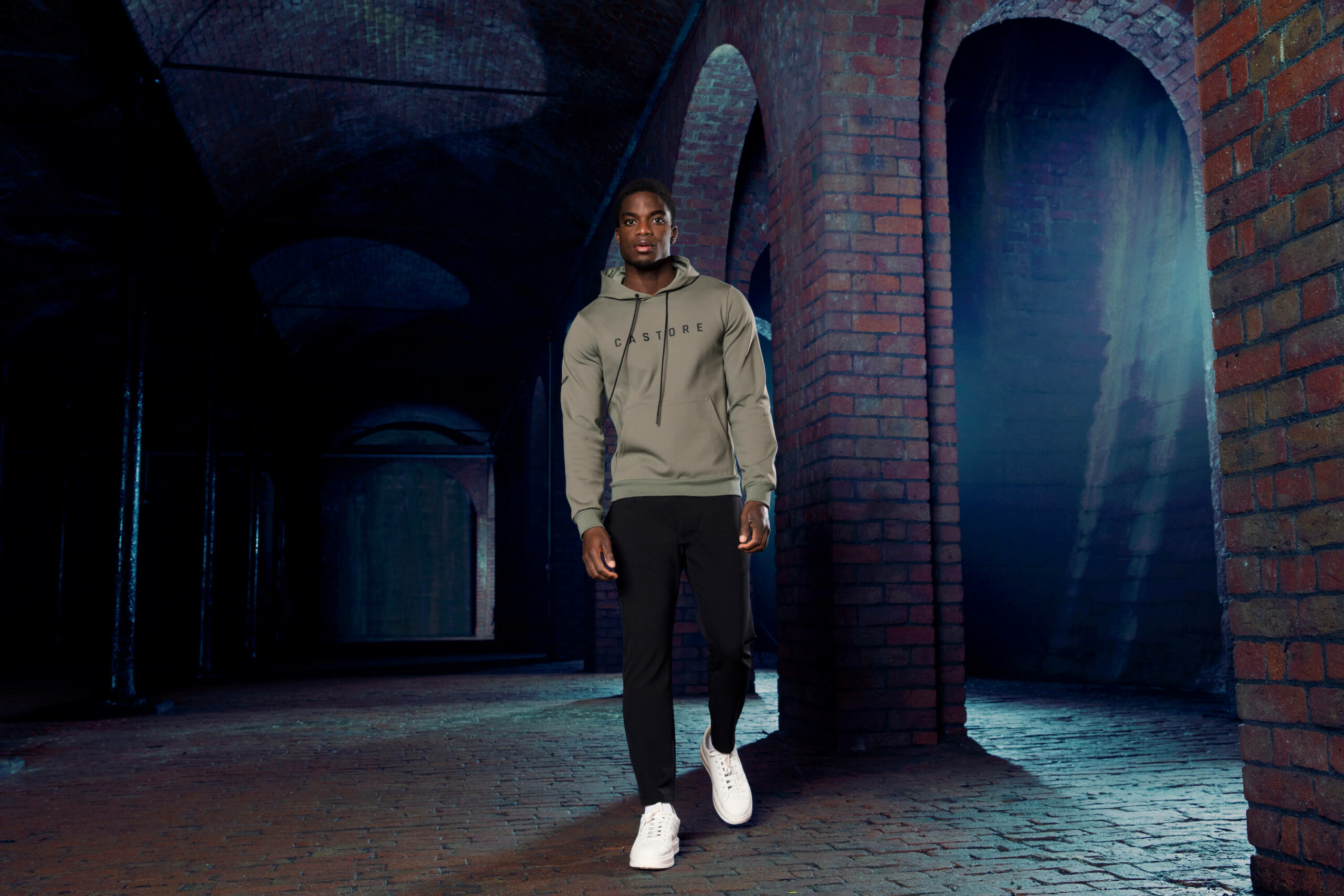 Male model in dark underground setting photographed wearing Castore sports apparel